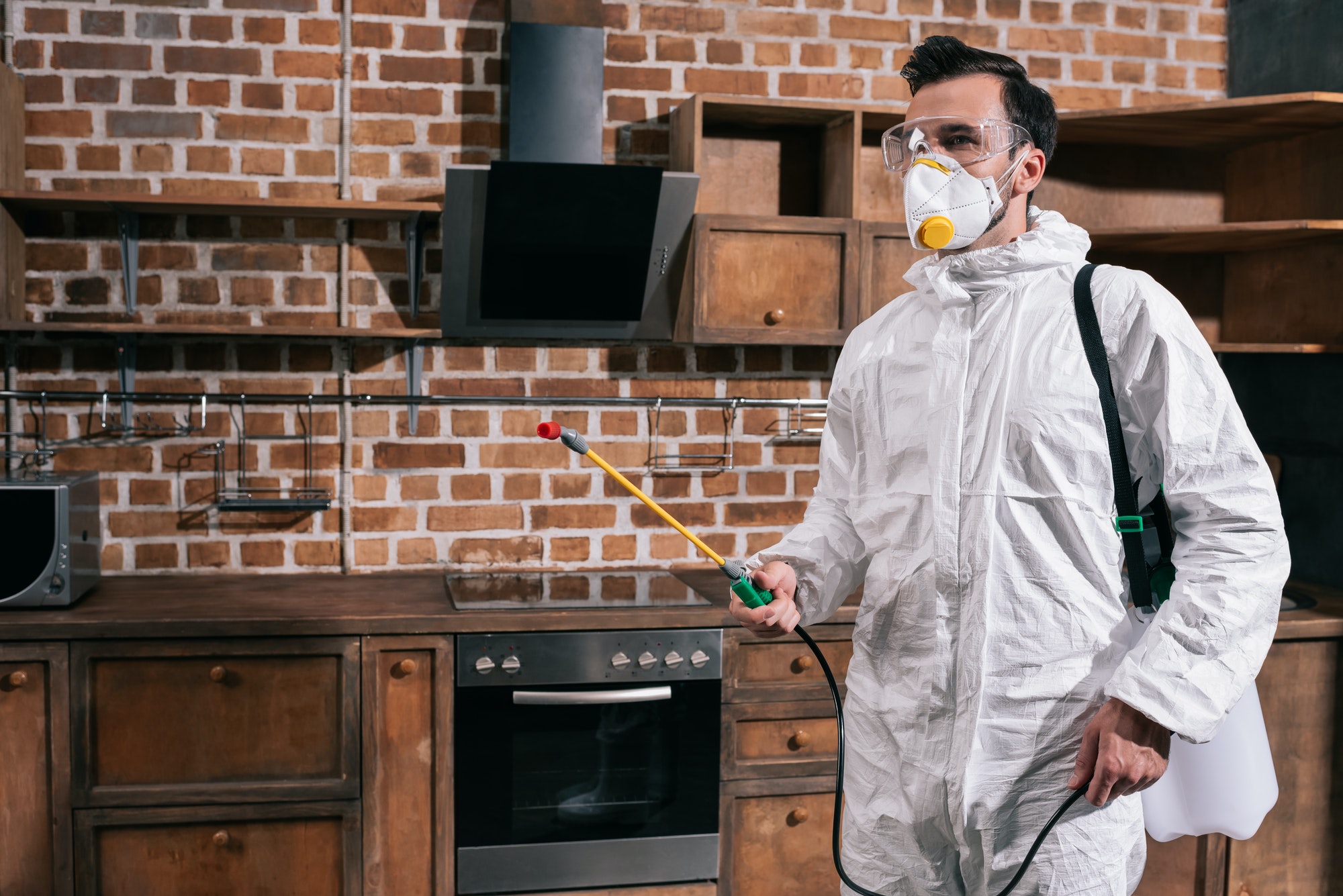 side-view-of-pest-control-worker-standing-with-sprayer-in-kitchen.jpg